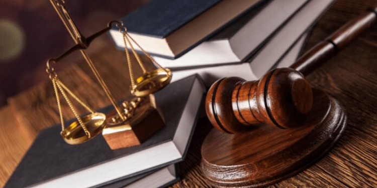Una bilancia un martelletto da giudice e diversi libri su un tavolo di legno.