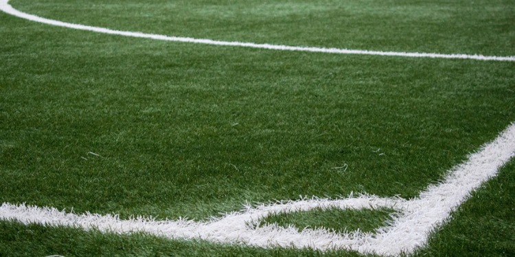 Manto erboso di un campo da calcio, con la lunetta del calcio d'angolo in evidenza.