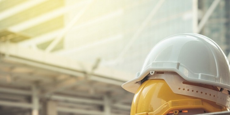 Due caschi di protezione in pila di fronte a un cantiere di un palazzo.