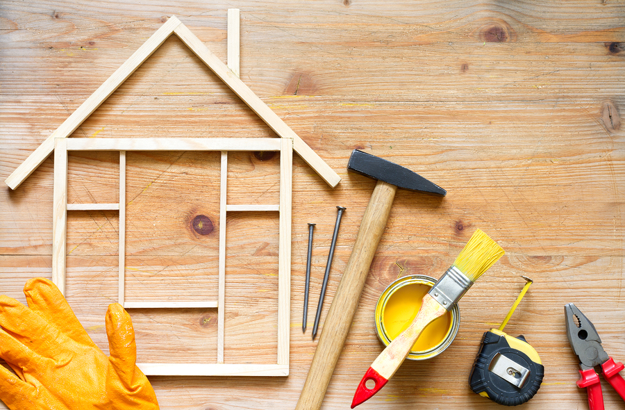 Su un tavolo ci sono strumenti di lavoro e una casa stilizzata con assi di legno.